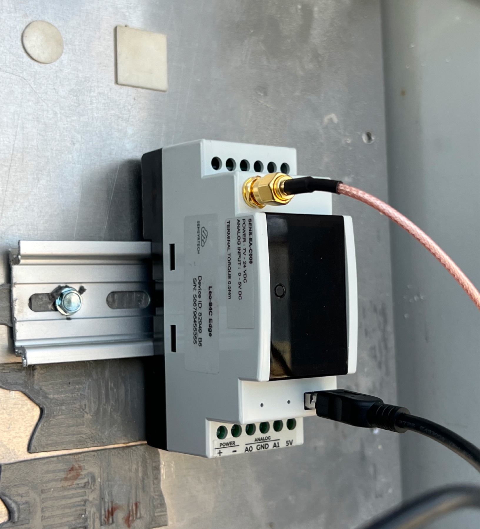 Leo-84C edge module mounted on DIN rail with SMA antenna and labeled analog terminals
